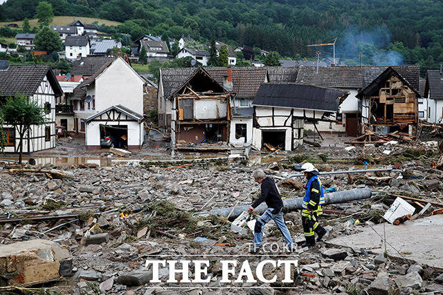15일(현지시간) 독일 슐트에 대규로 홍수 피해가 발생한 가운데 소방관들이 잔해에 둘러싸인 주택가를 지나가고 있다. /슐트=로이터