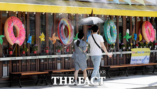 서울 등 수도권 지역에 폭염 경보가 내려진 18일 오후 서울 마포구 홍대입구역 인근에서 시민들이 양산으로 햇빛을 가리며 거리를 걷고 있다. /이선화 기자