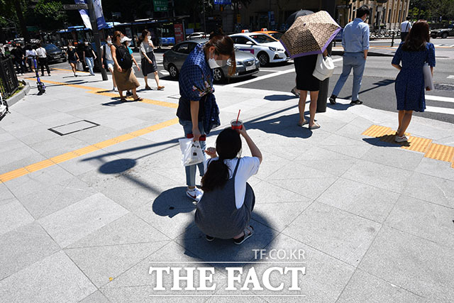 일년 중 가장 덥다는 절기 대서를 맞은 22일 오후 서울 종로구 세종대로 사거리에서 한 시민이 번호판 그림자에 앉아 아이스커피를 이마에 대고 있다. /남윤호 기자