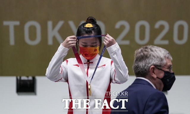 2020 도쿄올림픽 첫 금메달리스트인 중국 사격 국가대표 양첸이 메달을 스스로 목에 걸고 있다. /도쿄=AP.뉴시스