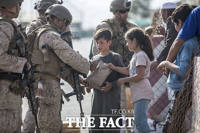 아프간 아이들에게 전투 식량 나눠주는 미 해병대 병사.