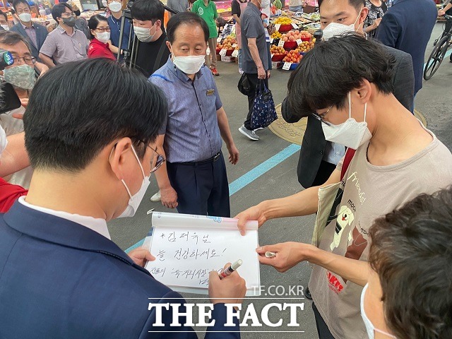 박용진 의원이 2일 청주 육거리시장에서 만난 20대로 보이는 청년에게 사인을 해주고 있다. / 청주=전유진 기자