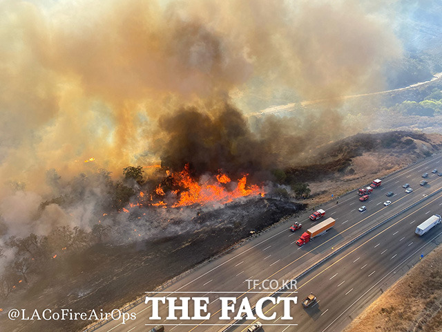 11일(현지시간) 오후 미국 로스앤젤레스 카운티 북부에서 발생한 산불이 바람을 타고 빠르게 번지면서 인근 고속도로를 이용하는 차량을 위협하고 있다. /캘리포니아=AP.뉴시스