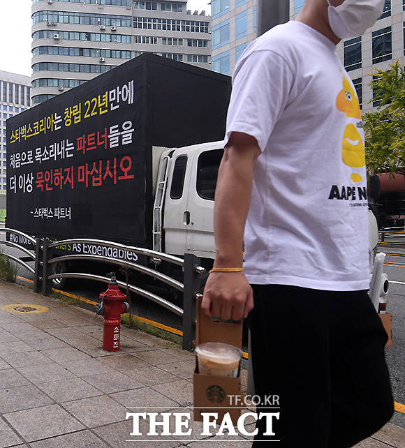 스타벅스 매장 직원(파트너)들이 과도한 마케팅으로 인한 처우 개선을 요구하는 트럭시위에 나선 가운데, 8일 오전 서울 중구 한 매장에서 커피를 구매한 시민이 트럭을 지나치고 있다. /이새롬 기자