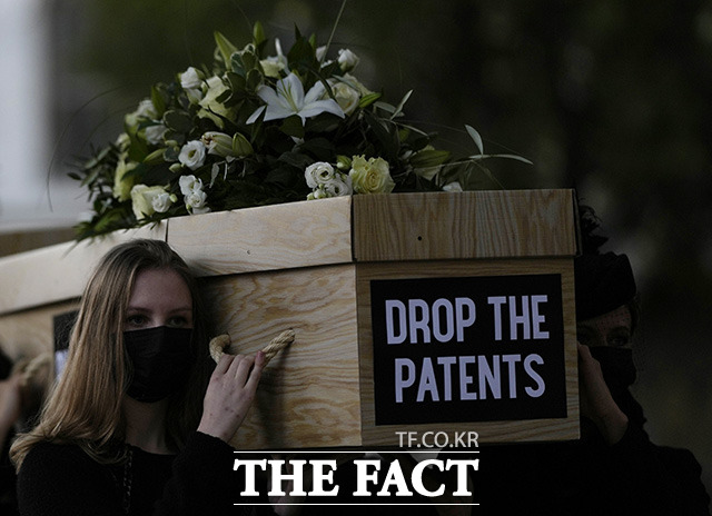 12일(현지시간) 영국 런던의 시민들이 전 세계 코로나19 사망자 수를 강조하는 모형 관을 들고 행진하고 있다. 이들은 가난한 나라 국민의 코로나19 백신 접종을 위해 다국적 대형 제약회사들이 코로나19 백신에 대한 특허를 포기할 것을 촉구했다./AP.뉴시스