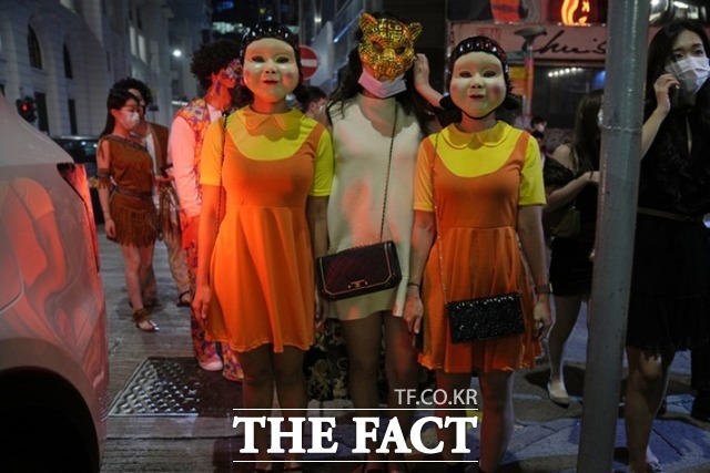 핼러윈 데이를 하루 앞둔 30일 오후 홍콩의 한 거리에서 시민들이 넷플릭스 오리지널 한국 시리즈 오징게임의 영희 의상을 입고 있다. /홍콩=AP.뉴시스
