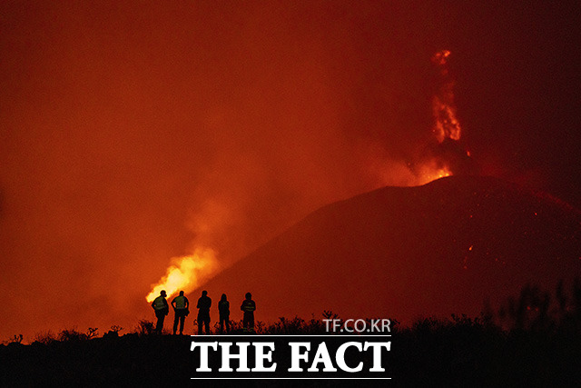 2일(현지시간) 스페인 카나리아 제도 라팔마섬 화산에서 용암이 흘러내리는 모습을 경찰과 구조대가 바라보고 있다. /라팔마=AP.뉴시스