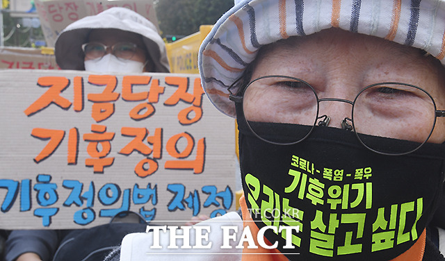 집회에 참석한 시민들이 마스크와 피켓에 쓴 글귀로 기후정의를 촉구하고 있다.