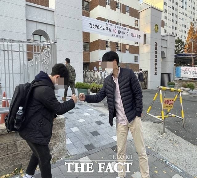 2022학년도 대학수학능력시험일인 18일 오전 경남 김해가야고등학교 앞에서 한 교사가 학생들과 주먹 인사를 나누며 응원하고 있다./경남=강보금 기자