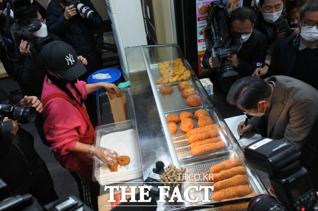 목포 동부시장에 방문한 이재명 민주당 대선후보가 시장안 청년창업자가 운영하는 가게에 들러 튀김을 구입하면서 방문 기념 글을 남기고 있다. /목포=김대원 기자