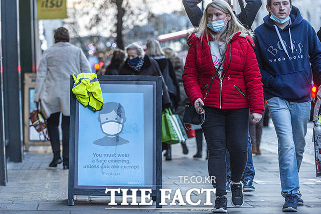 9일(현지시간) 영국 런던 나이츠브릿지 일대에서 시민들이 마스크를 착용을 권고하는 표지판을 지나가고 있다. /런던=신화.뉴시스