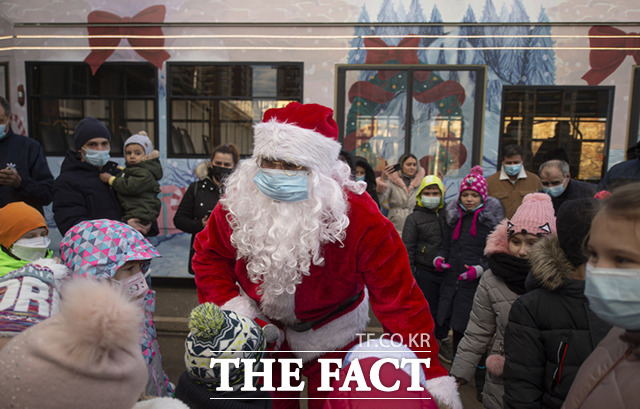 19일(현지시간) 루마니아 수도 부쿠레슈티의 한 대중교통 회사가 크리스마스 행사를 열어 크리스마스 주제로 꾸민 트램 앞에서 산타클로스 복장을 한 사람이 어린이들을 맞이하고 있다. /부쿠레슈티=AP.뉴시스