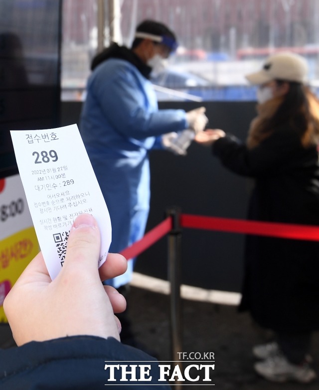 코로나19 신규 확진자가 1만 4518명으로 집계된 27일 오전 서울 중구 서울역 광장 임시선별검사소를 찾은 시민들이 검사를 받기 위해 번호표를 뽑고 있다. / 이새롬 기자