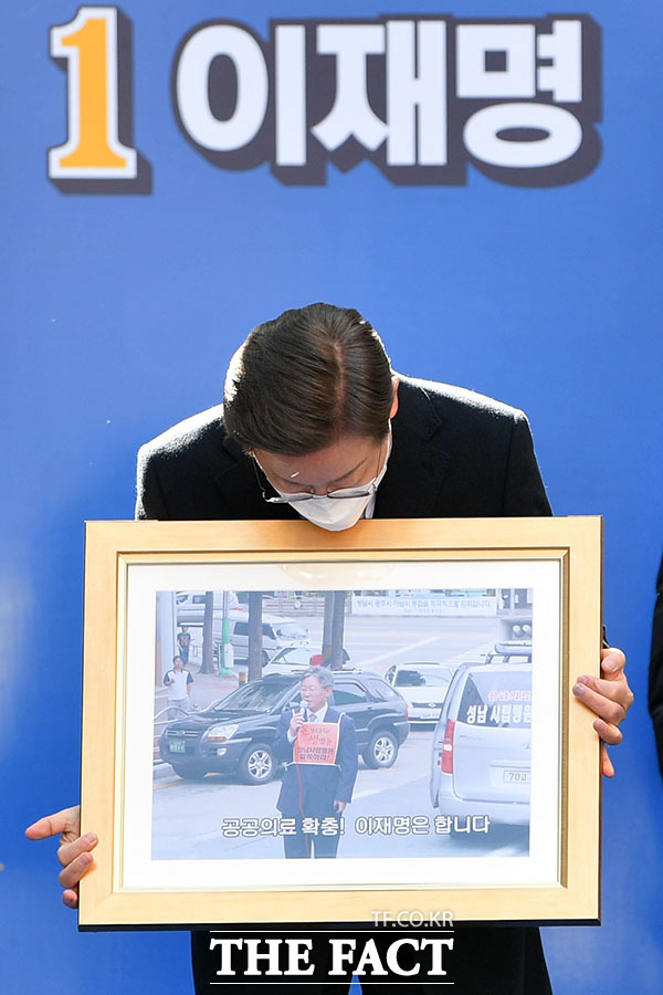 이날 집중유세에서 성남 시립병원 설립운동 당시 사진을 선물받은 이재명 후보가 사진 속 자신의 모습을 바라보고 있다.