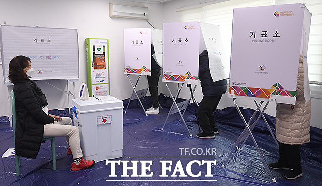 기표소에서 신중히 투표하는 유권자들.