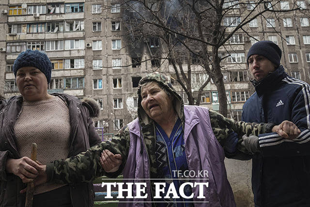 러시아의 우크라이나 침공이 이어지는 가운데 8일(현지시간) 우크라이나 마리우폴 주민들이 포격으로 파손된 아파트 거리에서 벗어나고 있다. /마리우폴=AP.뉴시스