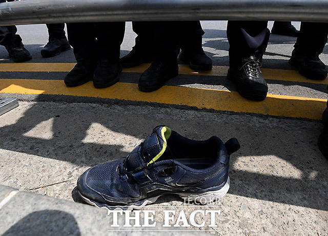 소주병을 투척한 현행범이 경찰에 체포되며 신발 한 짝이 남아 있다.
