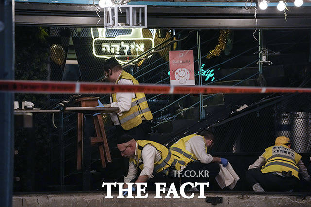 7일(현지시간) 이스라엘 텔아비브의 시내에서 총기 난사 사건이 발생한 가운데 구조 대원들이 피해 현장의 핏자국을 닦아내고 있다. /텔아비브=AP.뉴시스