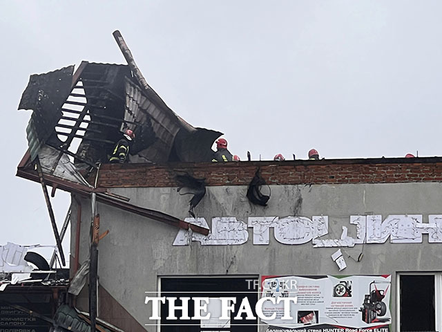 러시아군 미사일 공습을 받은 후 타이어 상점 잔해를 치우는 구조대원들.