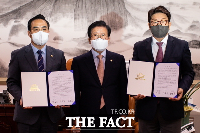 22일 민주당 박홍근(왼쪽), 국민의힘 권성동 원내대표가 박병석 국회의장(가운데)이 제안한 중재안을 들고 포즈를 취하는 모습. /국회사진취재단