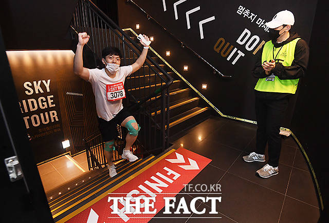 123층 마지막 계단을 오르는 참가자가 양 손을 번쩍 들어보이고 있다.