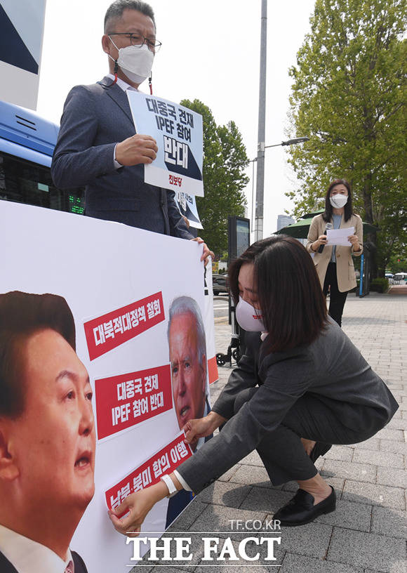 김재연 진보당 상임대표가 윤석열-바이든 사진에 구호 스티커를 붙이고 있다.
