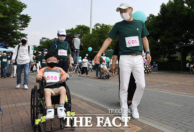 휠체어 탄 아동과 함께 걷는 유 대표(오른쪽).