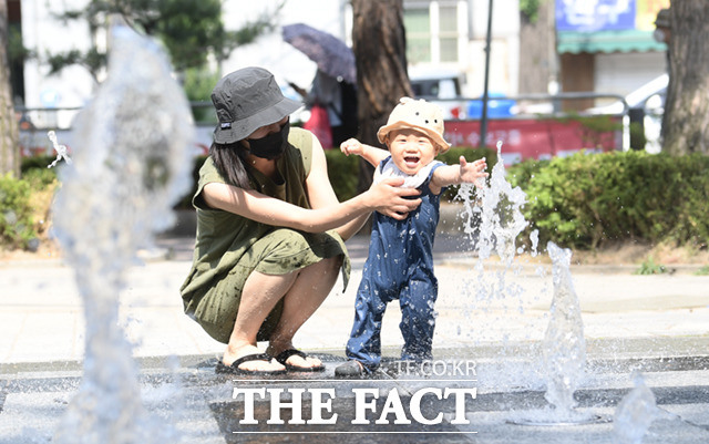 서울 낮기온이 30도까지 오르며 한여름 날씨를 보인 24일 오후 서울 강북구 솔밭공원 바닥분수를 찾은 엄마와 아기가 물놀이를 즐기며 더위를 식하고 있다. /이새롬 기자