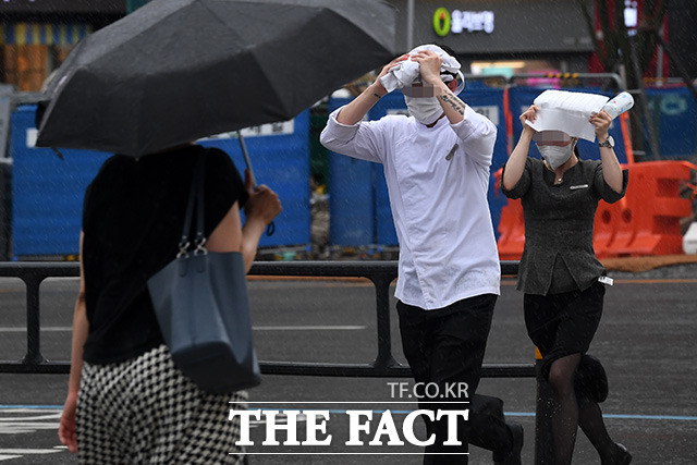 장마가 이어지며 전국적으로 장맛비가 내리는 29일 오후 서울 종로구 광화문 네거리 일대에서 우산을 준비하지 못한 시민들이 머리를 가린 채 비를 피하고 있다. /남용희 기자
