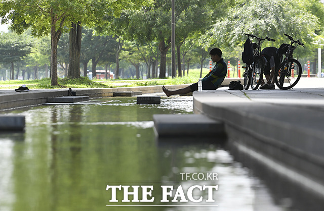 초복을 하루 앞둔 15일 오전 서울 영등포구 한강공원에서 한 시민이 더위를 피해 한강물에 발을 담그고 있다. /윤웅 기자