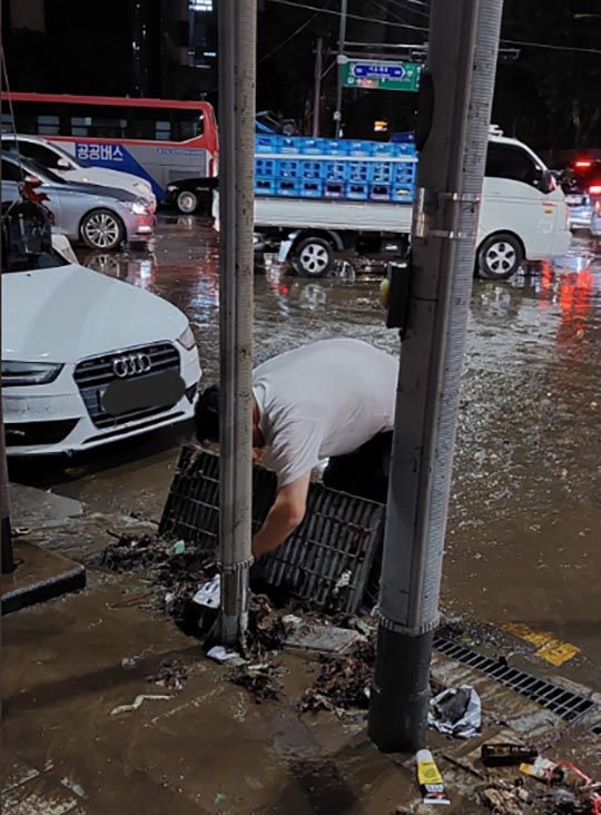 한 시민이 강남역 한복판에서 배수관에 쌓여있는 쓰레기를 맨손으로 건져내고 있다. /사진출처-@museun_happen 트위터