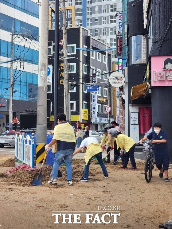 부산 수영구청 직원들이 6일 수영구에 있는 광안리해수욕장 주변 인도를 덮친 모래를 걷어내고 있다. /부산=김신은 기자.