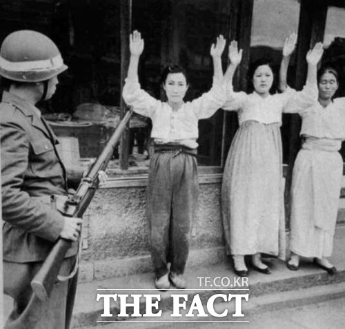 여순사건 당시 한 병사가 민간인들을 상대로 위협하며 손을 들게 하고 있다. /더팩트 DB