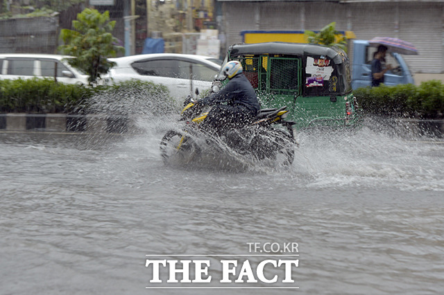 방글라데시 남부 해안에 사이클론 시트랑이 상륙한 가운데 24일(현지시간) 수도 다카의 거리에 차들이 물에 잠긴 도로를 아슬아슬하게 지나가고 있다. /다카=AP.뉴시스