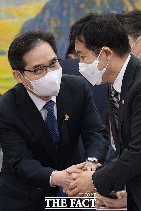 김주현 금융위원장(오른쪽)과 한기정 공정거래위원장이 회의에 참석해 악수하고 있다.
