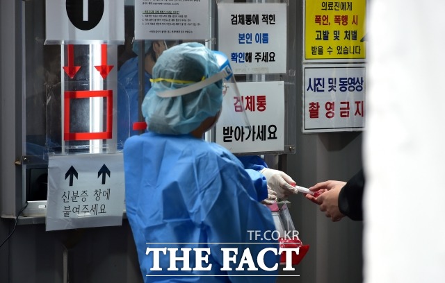 국내 코로나19 신규 확진자가 6만5253명 발생했다. 사진은 한 선별진료소에서 의료진이 검체통을 건네고 있다./뉴시스