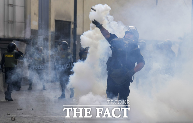 페루 곳곳에서 대통령 탄핵 반대 시위가 일어나는 가운데 12일(현지시간) 페루 리마에서 한 경찰관이 페드로 카스티요 전 대통령 지지자들에게 최루탄을 던지고 있다. /리마=AP.뉴시스
