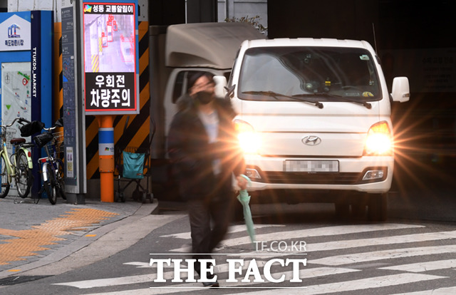 13일 오후 서울 성동구 성수역 앞 우회전 교차로에서 한 시민이 보행하는 가운데, 우회전 차량이 도로에 진입하고 있다.
