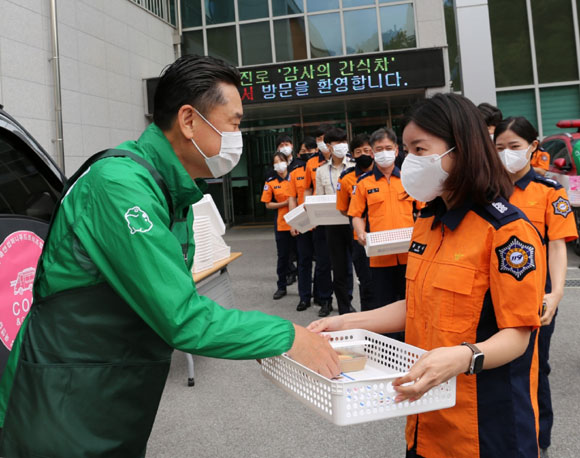 김인규(왼쪽) 하이트진로 대표가 소방공무원에게 간식을 전달하고 있다. /하이트진로 제공