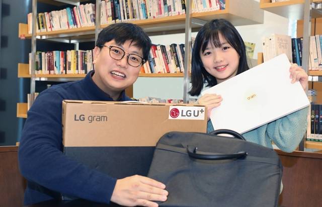 LG유플러스 임직원이 초등학교 입학을 앞둔 자녀와 선물로 받은 노트북을 소개하고 있다. /LG유플러스 제공