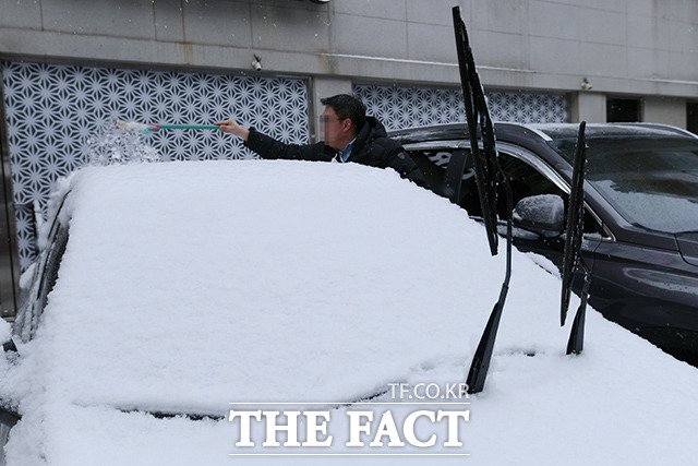 이른 아침부터 전국 곳곳에 눈이 내리면서 서울 등 중서부 지방에 대설주의보가 내려졌다. 오전에 내린 폭설로 한 시민이 차에 쌓인 눈을 빗자루로 치우고 있다. /이선화 기자