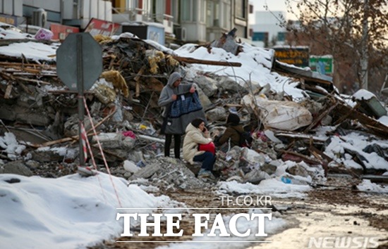 튀르키예 말라티아 주민들이 7일(현지 시각) 지진으로 무너진 건물 잔해 주변에 모여 앉아 있다. 지진 피해 주민들은 영하의 날씨에도 여진에 따른 추가 붕괴 위험으로 거리에서 밤을 지새우는 것으로 알려졌다./AP뉴시스
