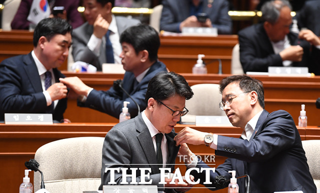 16일 서울 여의도 국회에서 열린 더불어민주당 의원총회에서 의원들이 서로의 옷깃에 태극기 배지를 달아주고 있다.