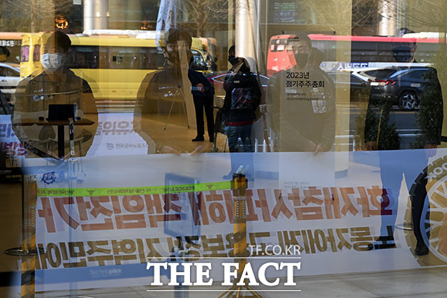 한국타이어앤테크놀로지 본사 앞을 찾은 한국타이어 노동자들이 입장발표 기자회견을 앞두고 있다. 사진은 내부 출입이 통제된 주주총회장 유리창에 비친 노동자들의 모습.