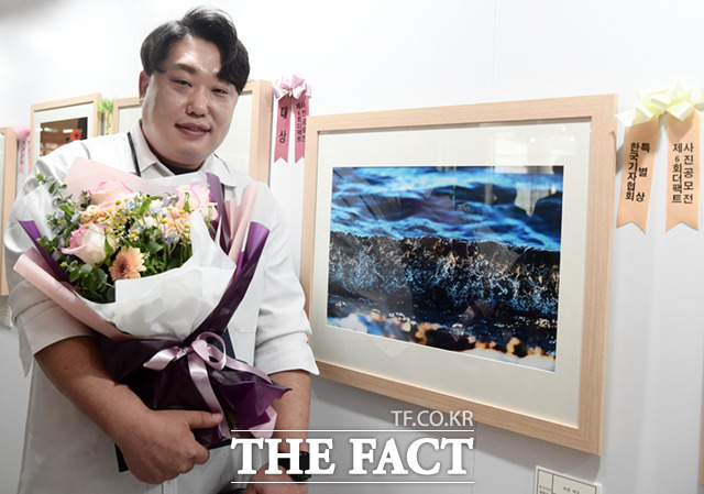 한국기자협회상 수상자인 김기중 씨가 작품과 함께 기념촬영하고 있다.