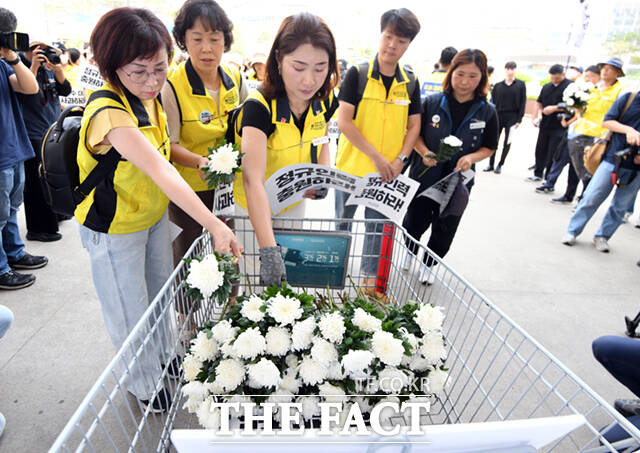 코스트코 마트노동자들이 근무 중 온열질환으로 사망한 고 김동호 씨의 49재 추모집회를 하며 카트에 헌화하고 있다.