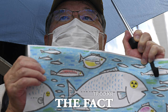 24일 일본 도쿄의 도쿄전력 본사 앞에서 오염수 해양 방류 반대 시위 참가자가 방사능에 오염된 물고기 그림을 들고 있다. /도쿄=AP.뉴시스