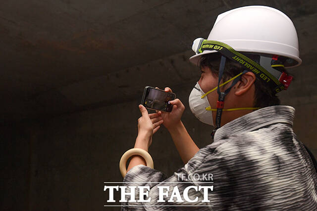 안전모와 마스크를 착용한 시민이 서울광장 지하 미개방 공간을 둘러보며 휴대전화로 내부를 촬영하고 있다.