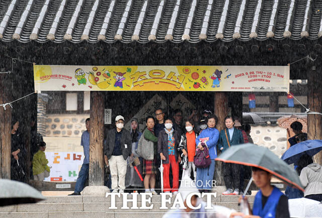 추석 연휴 셋째 날인 30일 오후 서울 중구 남산골 한옥마을을 찾은 시민들이 처마 밑에서 비를 피하고 있다.