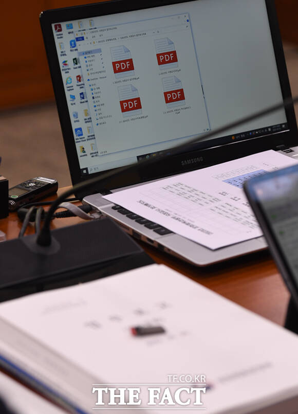 책상에 업무보고 책자와 동일한 내용이 담긴 USB, 해당 내용이 담긴 노트북이 보이고 있다.